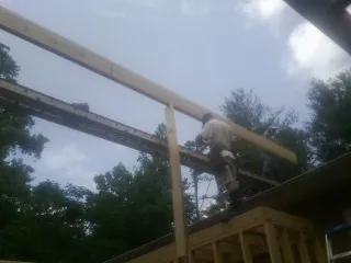 Carpenter setting a ridge beam over a new addition frame — Ice Dam Removal by Roofing Brothers in Galt