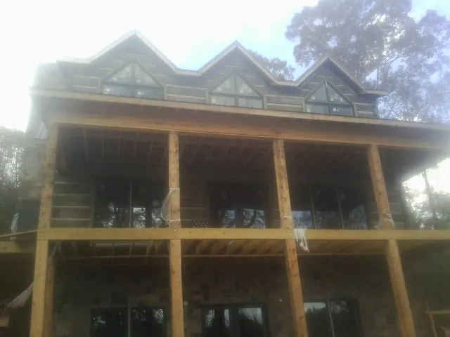 Dormers and porch framing on a large log home under construction — Roof Coating work by our crew in Galt