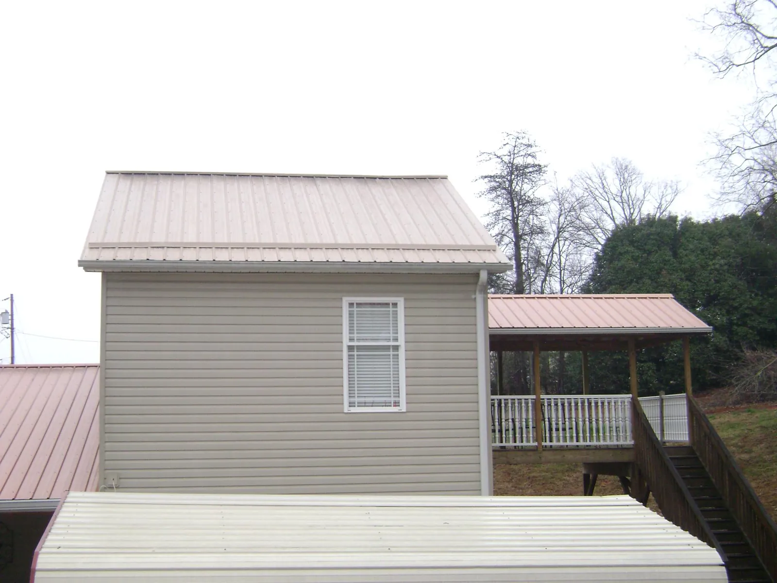 Tan metal roofs on a two story addition and attached porch, from a Roof Replacement job in Galt